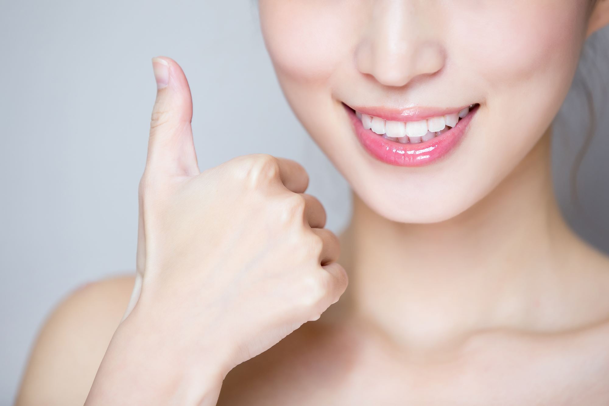 Close up of young woman after jaw surgery giving thumbs up
