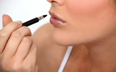 woman with makeup brush next to lips