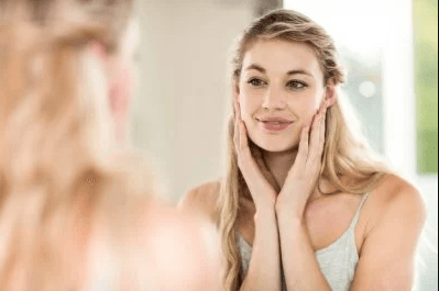 woman looking at face in the mirror