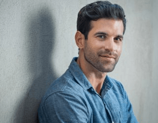 man up against wall smiling