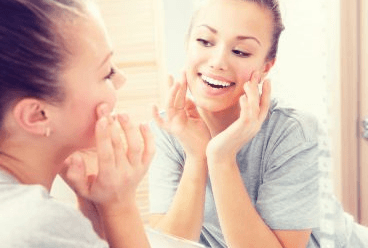 woman looking at face in the mirror